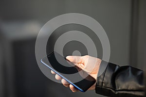 Closeup image of male hands with smartphone, searching internet or social networks, blurred background