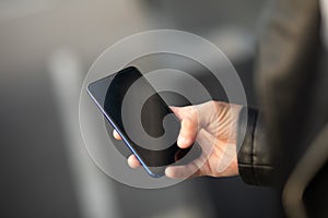 Closeup image of male hands with smartphone, searching internet or social networks, blurred background