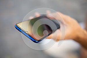 Closeup image of male hands with smartphone, searching internet or social networks, blurred background