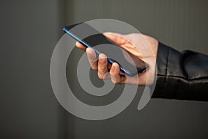 Closeup image of male hands with smartphone, searching internet or social networks, blurred background