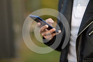 Closeup image of male hands with smartphone, searching internet or social networks, blurred background