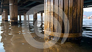 Closeup image of old collapsing wooden columns holding pier on the beach