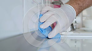 Closeup Image with Person Hands Wearing Protective Yellow Household Gloves Cleaning the Kitchen Furniture