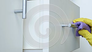 Closeup Image with Person Hands Wearing Protective Yellow Household Gloves Cleaning the Kitchen Furniture