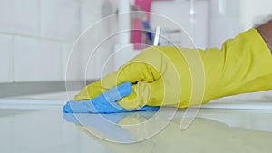 Closeup Image with Person Hands Wearing Protective Yellow Household Gloves Cleaning the Kitchen Furniture