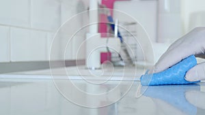 Closeup Image with Person Hands Wearing Protective Yellow Household Gloves Cleaning the Kitchen Furniture