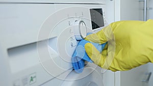 Closeup Image with Person Hands Wearing Protective Yellow Household Gloves Cleaning a Washing Machine