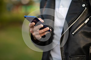 Closeup image of an unrecognizable young man holding mobile phone in hand, blurred background