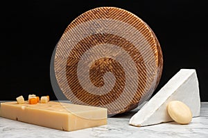 Closeup image of a white Akawi, Cheddar and Queso Blanco cheese and a small round cheese photo