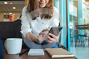 A woman holding , using and texting message from smart phone in cafe