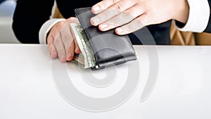 Closeup image of woman trying to close leather wallet full of money