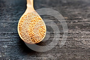 Mustard seeds in wooden spoon close up