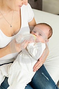 Closeup image of young mother feeding her baby boy in bed from b