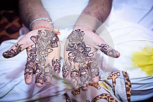 Closeup of an Indian man showing Mehndi on his hands during an event