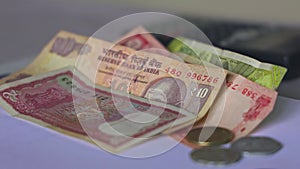 Closeup of Indian rupee coins falling over currency notes on a table