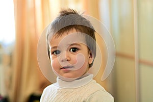 Closeup indoor portrait of a baby boy with naughty hair. The various emotions of a child.