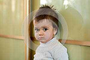Closeup indoor portrait of a baby boy with naughty hair. The various emotions of a child.