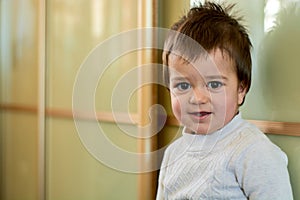 Closeup indoor portrait of a baby boy with naughty hair. The various emotions of a child.