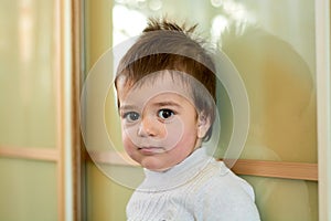 Closeup indoor portrait of a baby boy with naughty hair. The various emotions of a child.