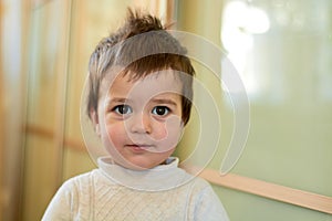 Closeup indoor portrait of a baby boy with naughty hair. The various emotions of a child.