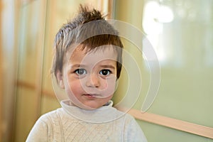 Closeup indoor portrait of a baby boy with naughty hair. The various emotions of a child.