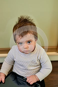 Closeup indoor portrait of a baby boy with naughty hair. The various emotions of a child.