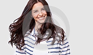 Closeup indoor portrait of beautiful brunette young woman with long hair smiling cheerfully. Charming female smile broadly showing