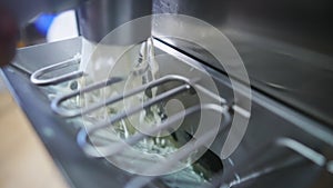 Closeup indoor shot of pasteurizer machine pouring ice cream into steel freezer. Ice cream manufacture concept