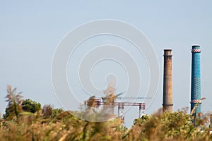 Closeup of industrial chimneys with blue sky on background