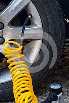 Closeup of inflating car tyre with electric pump.