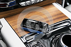 Closeup inside vehicle of wireless blue leather key ignition on natural wood panel. Wireless start engine key. Car key remote isol