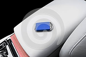 Closeup inside vehicle of wireless blue leather key ignition on natural wood panel. Wireless start engine key. Car key remote isol