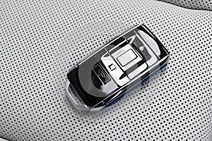 Closeup inside vehicle of wireless blue leather key ignition on white leather seat. Wireless start engine key. Car key remote isol