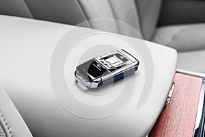 Closeup inside vehicle of wireless blue leather key ignition on white leather seat. Wireless start engine key. Car key remote isol