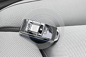 Closeup inside vehicle of wireless blue leather key ignition on white leather seat. Wireless start engine key. Car key remote isol