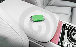 Closeup inside vehicle of wireless green leather key ignition on white leather seat. Wireless start engine key. Car key remote iso
