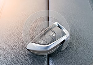 Closeup inside vehicle of wireless key ignition. Start engine key. Car key remote in black perforated leather interior. Car backgr