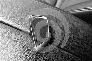 Closeup inside vehicle of wireless key ignition. Start engine key. Car key remote in black perforated leather interior. Modern car