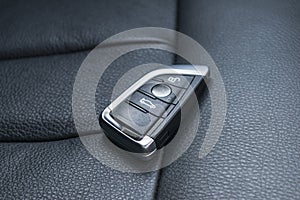 Closeup inside vehicle of wireless key ignition. Start engine key. Car key remote in black perforated leather interior. Modern car