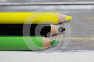 Closeup of isolated colorful black, green, yellow crayons on wood background - jamaica coalition concept