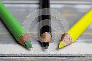 Closeup of isolated colorful black, green, yellow crayons on wood background - jamaica coalition concept