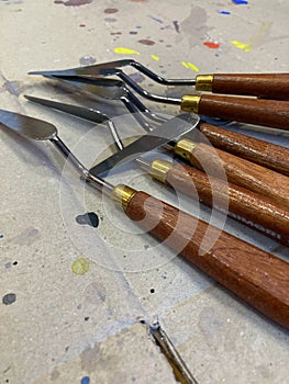 Closeup of isolated spatulas, painting tools on a cardboard background with drops of colored paint on an art lab