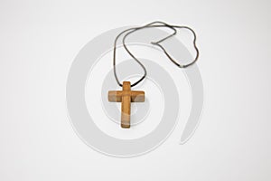 Closeup and isolated view of a small wooden cross on a string