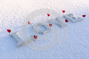 Closeup of Isolated Word & x22;Love& x22; from Wooden Pieces in the Snow on Sunny Winter Day with White Background with Red Heart