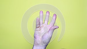 Closeup of isolated on yellow adult male hand counting from 0 to 5.