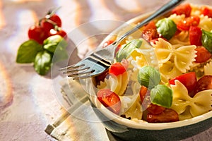 Closeup of Italian Farfalle pasta with tomatoes, basil and fork