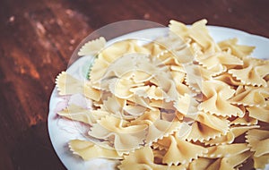Closeup of Italian farfalle pasta in a white plate on a wooden table