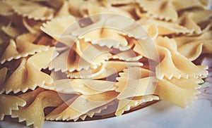 Closeup of Italian farfalle pasta in a white plate on a wooden table