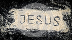 Closeup of JESUS word written on white sand