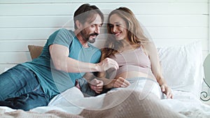 Closeup joyful pregnant couple talking in bed. Happy pregnant couple kissing